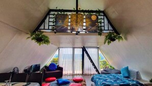A cozy, triangular room with a bed, a sofa, and a dining area. - Viewscape Nature Park Tanay powered by Cocotel (Tanay)