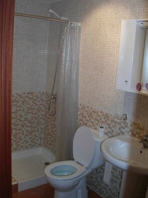 A bathroom with a shower, toilet, and sink.