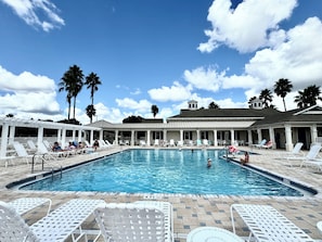 Una piscina con lettini e palme.