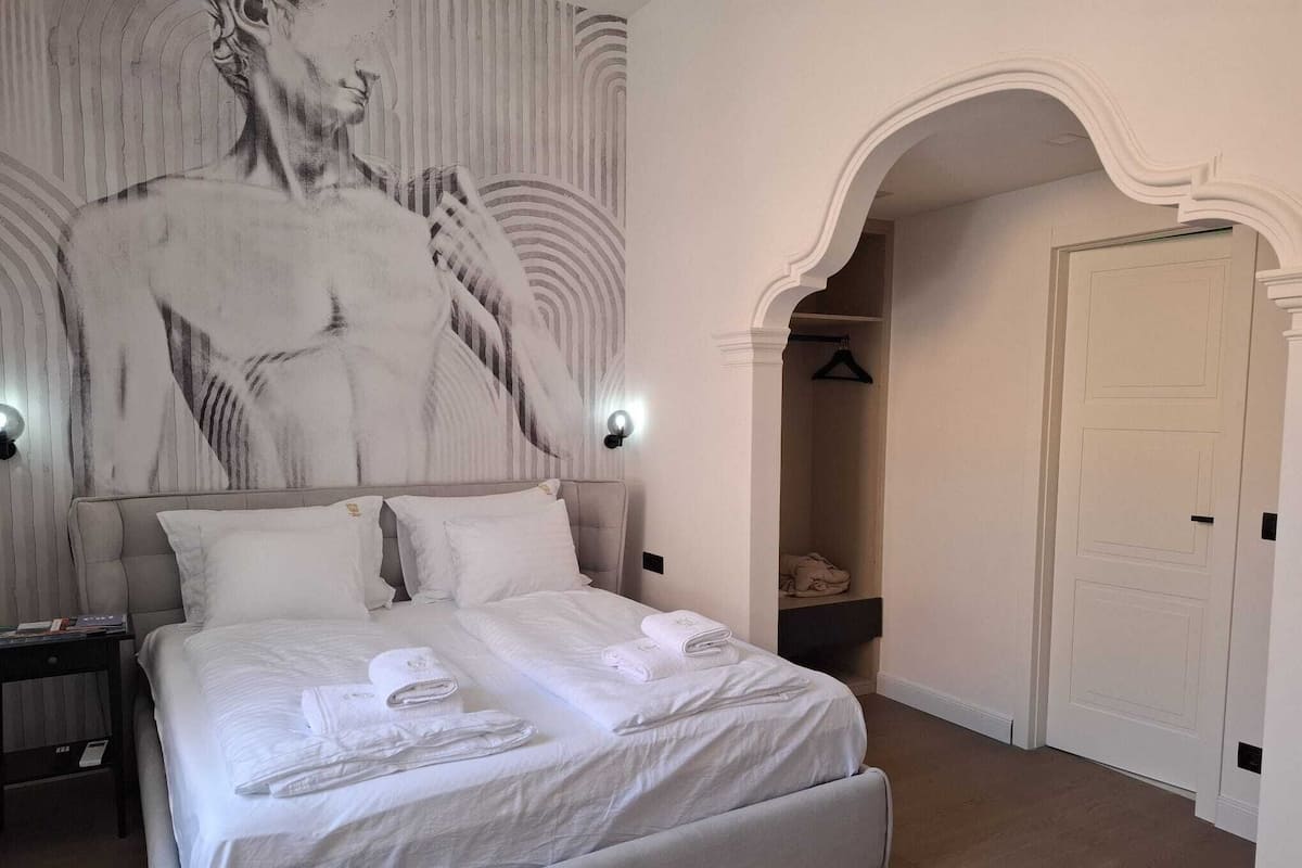 A bedroom with a large bed, a wardrobe, and a wall with a mural.