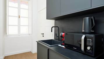 Une cuisine moderne avec un plan de travail noir, une machine à café et un four à micro-ondes.