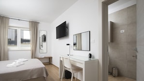 Una habitación de hotel moderna con cama, escritorio, silla, televisor y baño.