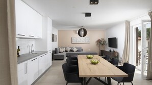 Una cocina moderna con armarios blancos, una mesa de comedor de madera y sillas negras.