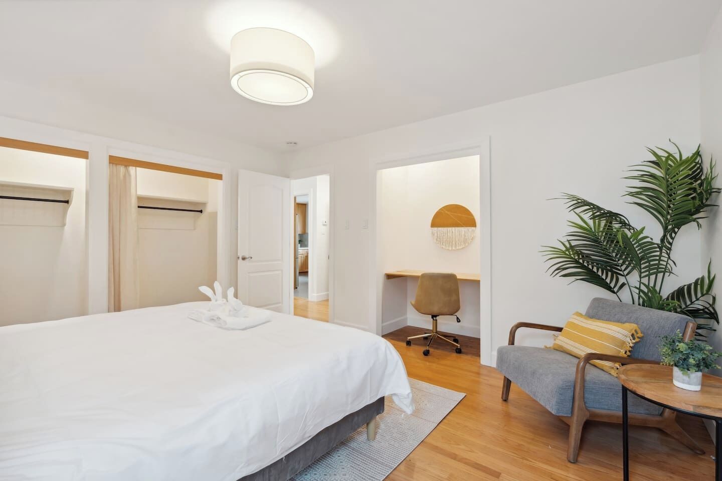 Ein modernes Hotelzimmer mit einem großen Bett, einem Schreibtisch, einem Sessel und einer Topfpflanze.