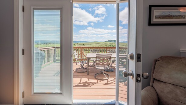A door leading to an outdoor deck with a view of a green landscape and a clear sky. - Mountain View Escape (Christiansburg)