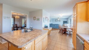 A spacious kitchen with granite countertops, wooden cabinets, and a dining area with a large table and chairs. - Mountain View Escape (Christiansburg)