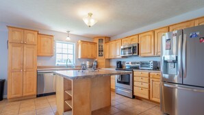 A modern kitchen with wooden cabinets, stainless steel appliances, and a central island. - Mountain View Escape (Christiansburg)