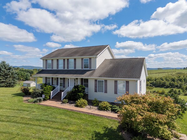 Une maison à deux étages avec un porche à l’avant, une allée couverte et une pelouse bien entretenue.