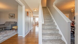 A spacious living area with hardwood flooring, a grey carpeted staircase, and a grey sofa. - Mountain View Escape (Christiansburg)