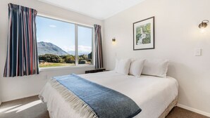 Un dormitorio con una cama grande, una ventana con cortinas, un cuadro en la pared y una lámpara.