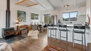 Una cocina moderna con una isla central, taburetes de bar, estufa y ventanas amplias.