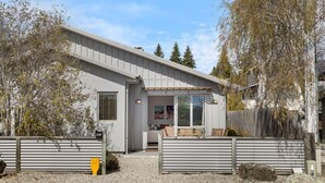 A modern single-story house with a covered porch, a small front yard, and a gravel driveway. - Amazing Location! Central 2 bedroom Unit (Wānaka)