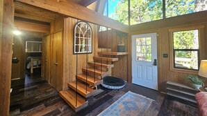 Un intérieur en bois avec un escalier en colimaçon, une porte avec une fenêtre et un tapis sur le sol.