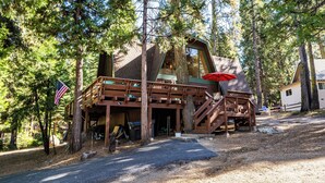 Une cabane dotée d’une terrasse en bois, d’un escalier et d’une grande fenêtre.
