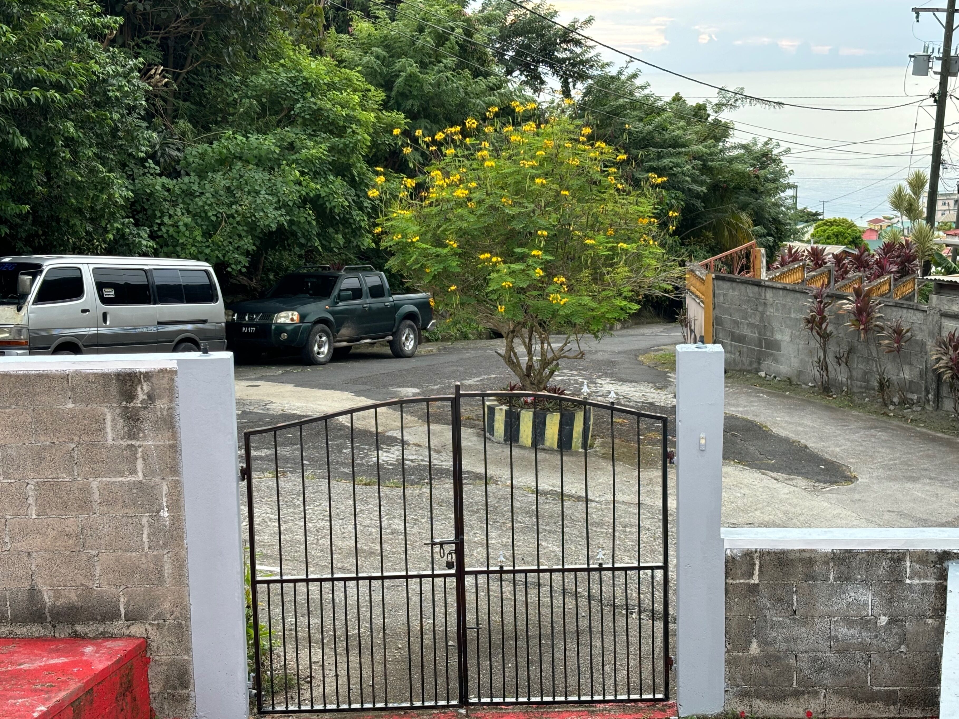 A gated parking area with a tree and a parked vehicle.