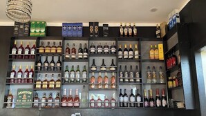 A bar area with multiple shelves of various liquor bottles, a phone, and a menu board. - Wendy's Suites  (Abeokuta)