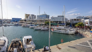 Una marina con varias embarcaciones amarradas, un velero llamado 'Sail Away', y edificios al fondo.