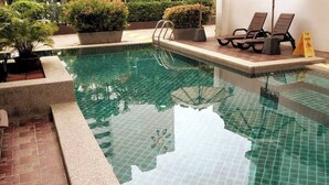 A swimming pool with a tiled edge, a ladder, and lounge chairs. - 6-15 - 1 Bdr Condo With Balcony and Shared Pool (Patong)