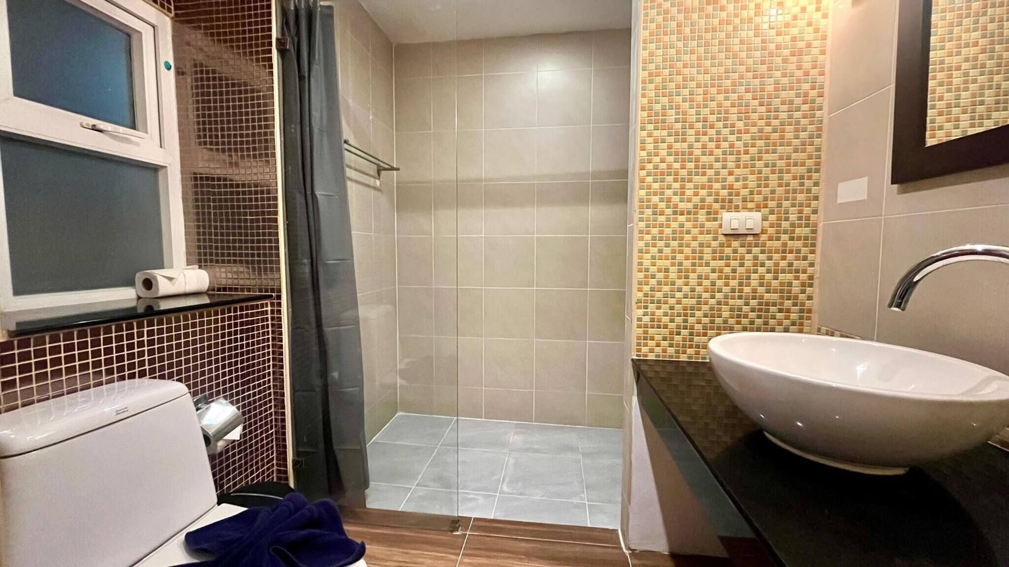 A bathroom with a toilet, a sink, and a shower area.