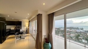 A modern hotel room with a balcony, a kitchen area, and a view of the city and sea. - A11 - 2 Bdr Condo, Stunning Sea View, Karon Beach (Karon)