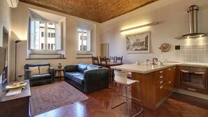 A modern kitchen with a brick ceiling, large windows, and a central island. - Piazza Salvemini Elegant (Florence)