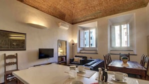 A room with a large table, a television, a sofa, and a window. - Piazza Salvemini Elegant (Florence)