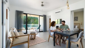 Un salon moderne avec un canapé, une table à manger et des chaises. Il y a un balcon équipé de mobilier d’extérieur.