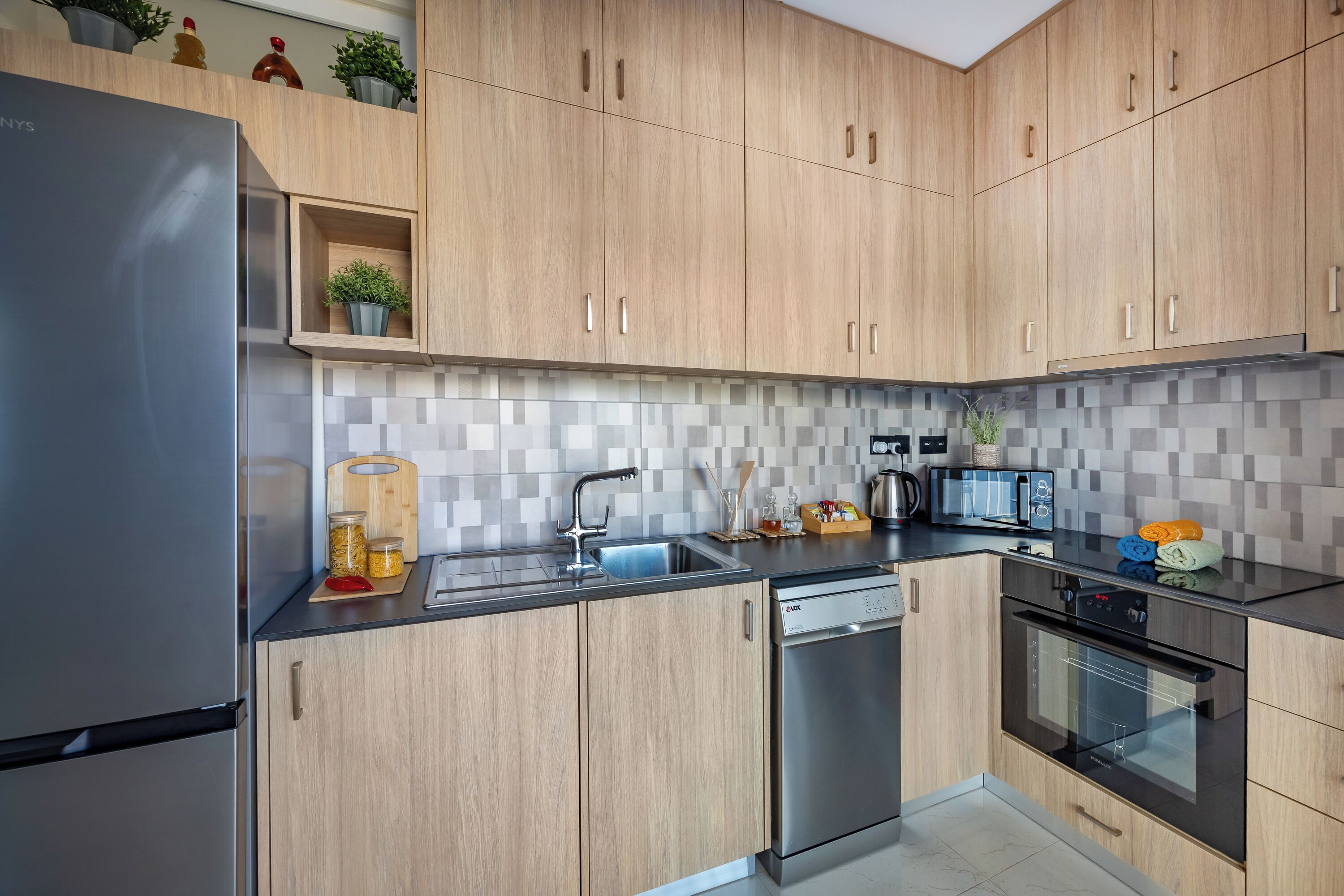 Una cocina moderna con armarios de madera, electrodomésticos de acero inoxidable y salpicadero de azulejos.