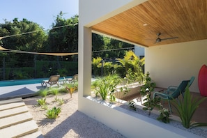 Une terrasse extérieure moderne, dotée d’une piscine, d’un espace salon et d’une végétation luxuriante.