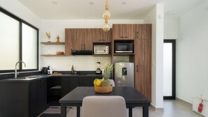 Une cuisine moderne avec des meubles de rangement aux couleurs sombres, un plan de travail noir et une table à manger en bois.