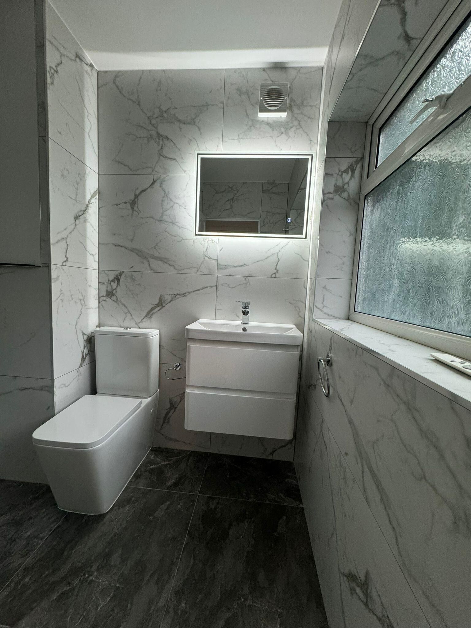 A compact bathroom with a toilet, sink, and mirror.