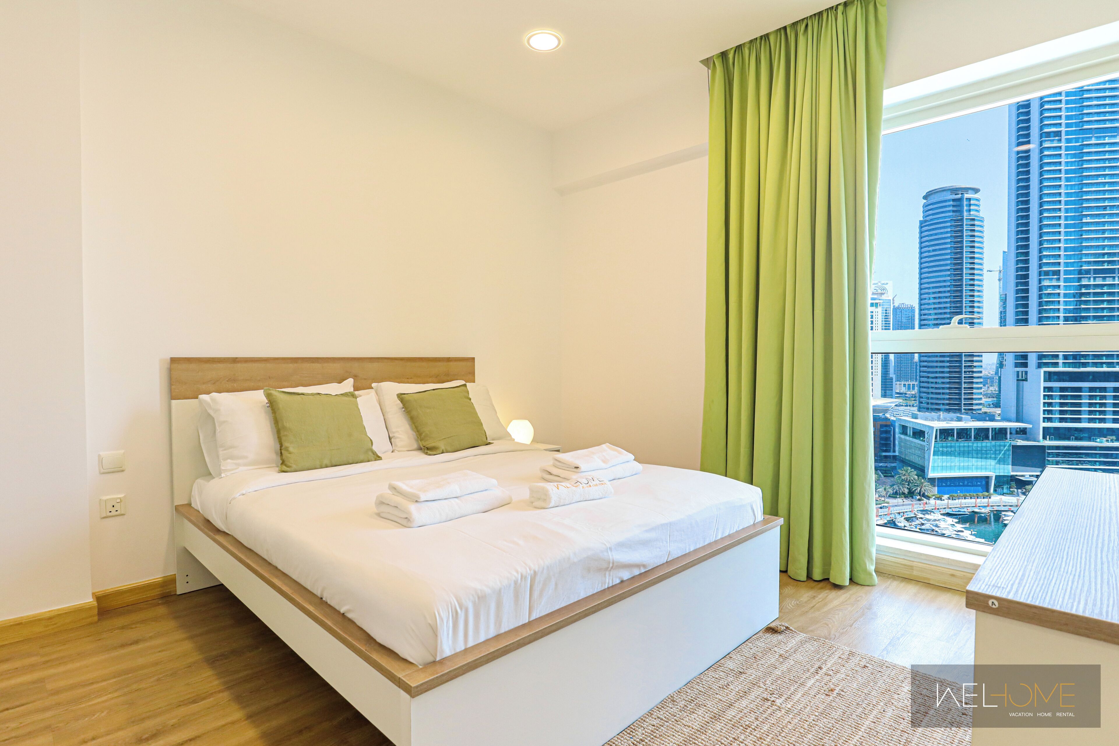 Ein modernes Hotelzimmer mit einem großen Bett, Blick auf die Stadt und einem grünen Vorhang.