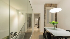 A modern dining area with a glass partition, a staircase, and a dining table with chairs. - The Architect - Exclusive Loft in Ponteroso (Trieste)