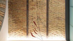 A room with exposed brick walls, a modern light fixture, and a partial view of a window. - The Architect - Exclusive Loft in Ponteroso (Trieste)