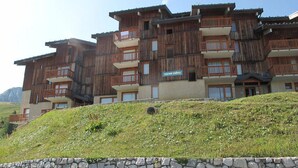 A multi-story wooden building with balconies, a stone wall in the foreground, and a sign that reads "Squaw Valley."