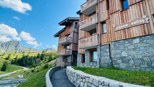 A wooden building with balconies and a stone wall, labeled "Squaw Valley".