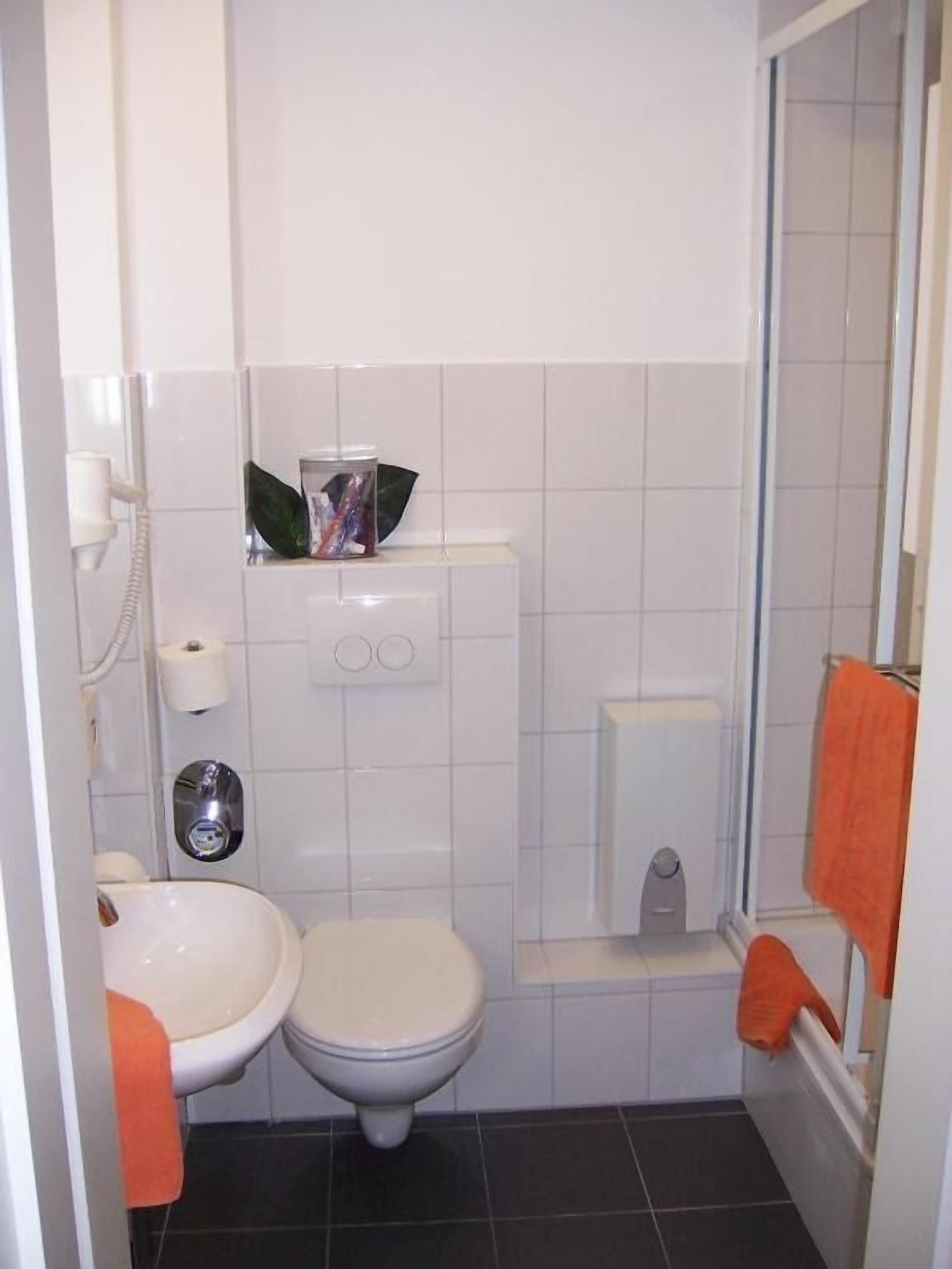 A small bathroom with a toilet, sink, and shower.