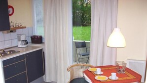 A small kitchen with a dining area, a coffee maker, and a table set with plates and cups. - Darz Gästezimmer (Hamburg)