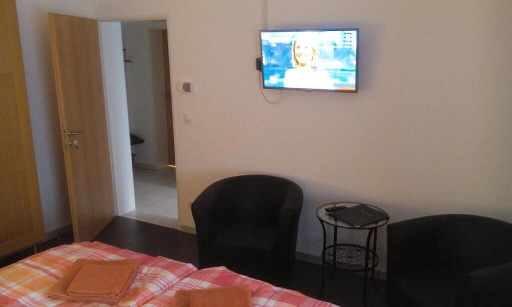 Una habitación de hotel con una cama, dos sillas, una mesita y un televisor fijado a la pared.