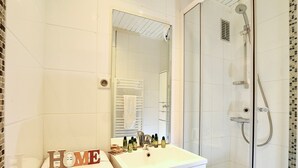 Une salle de bain avec un meuble-lavabo blanc, un miroir, une douche et une pancarte indiquant « MAISON ».
