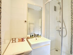 Ein Badezimmer mit weißem Waschtisch, einem Spiegel, einer Dusche und einem Schild mit der Aufschrift 'HOME'.