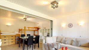 Une pièce confortable avec un lit superposé, un canapé, une table à manger avec des chaises et une bibliothèque.