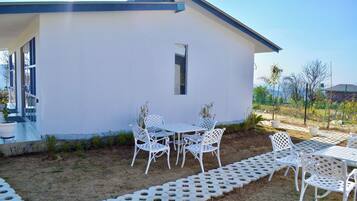 Une maison moderne dotée d’un patio aménagé avec des chaises et une table en métal blanc.