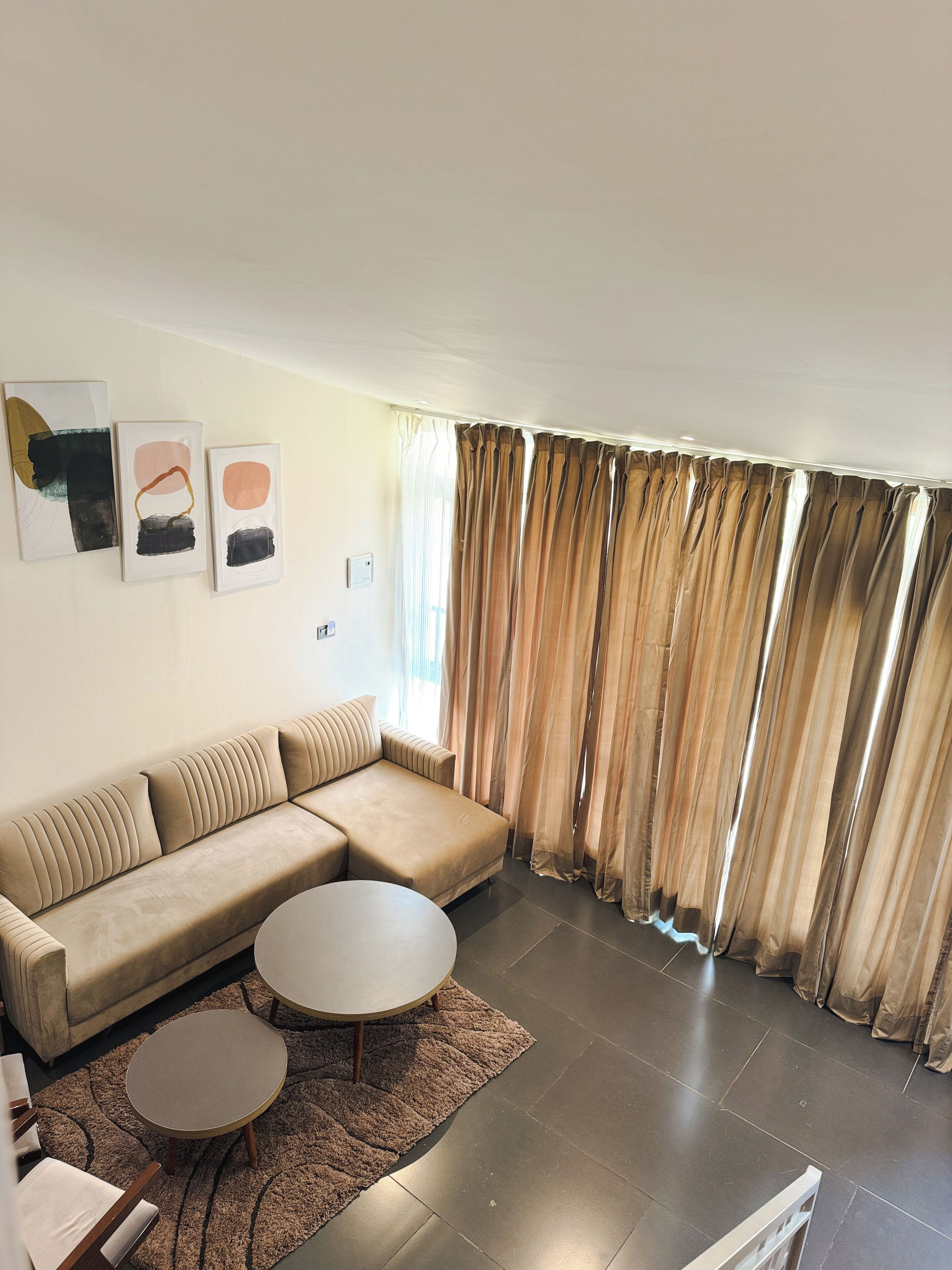 A modern living room with a sectional sofa, two round coffee tables, and abstract wall art.