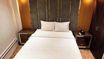 A large bed with a dark headboard and two bedside tables, each with a lamp.