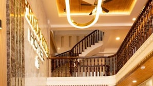 A hotel lobby with a grand staircase, a plush sofa, and a glass coffee table. - Phuoc Hung 3 (Long Chau)