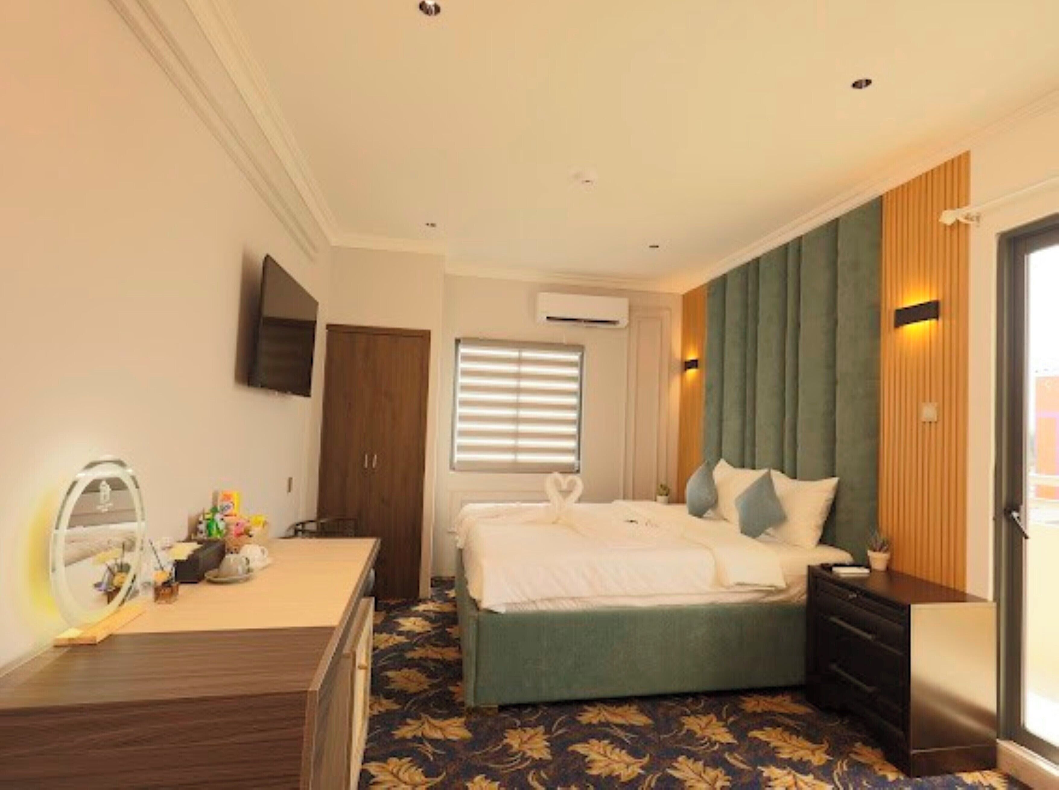 Una habitación de hotel con cama, escritorio, armario y ventana con persianas.
