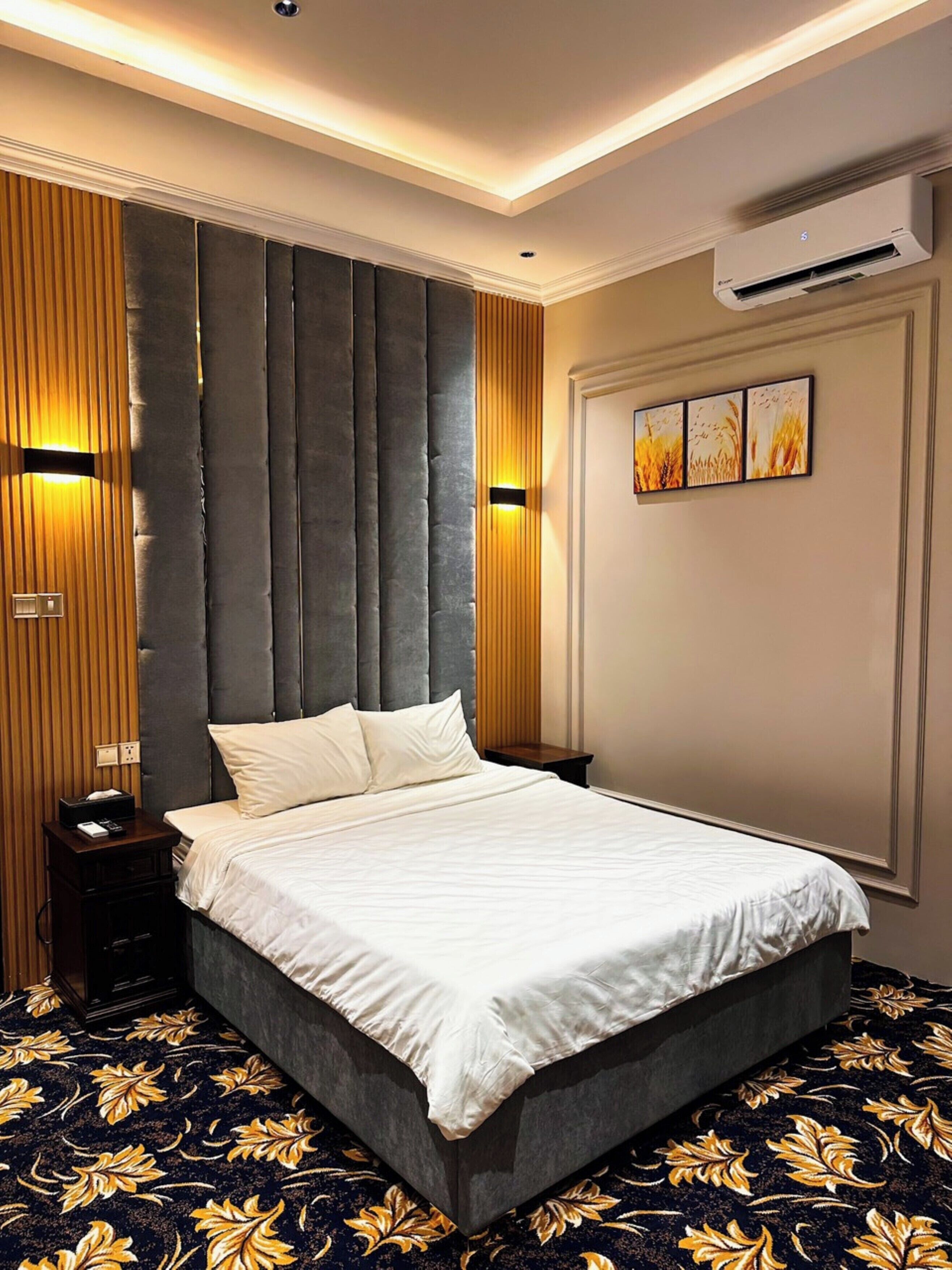 Una habitación de hotel moderna con una cama grande, un panel de pared de madera y una lámpara en el techo.