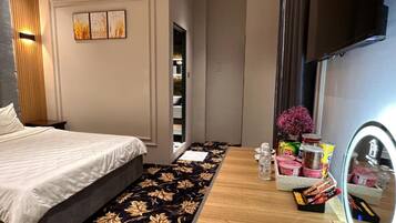 A modern bedroom with a bed, a vanity with a mirror, and a small table with toiletries.