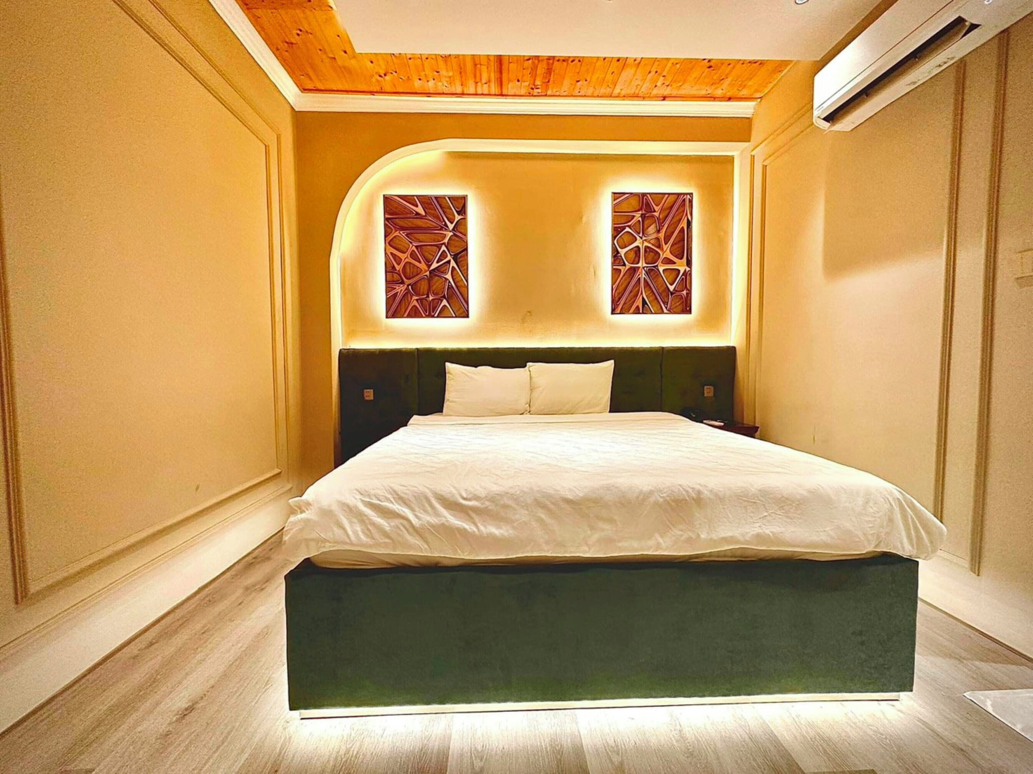 A modern bedroom with a large bed, wooden ceiling, and decorative wall panels.